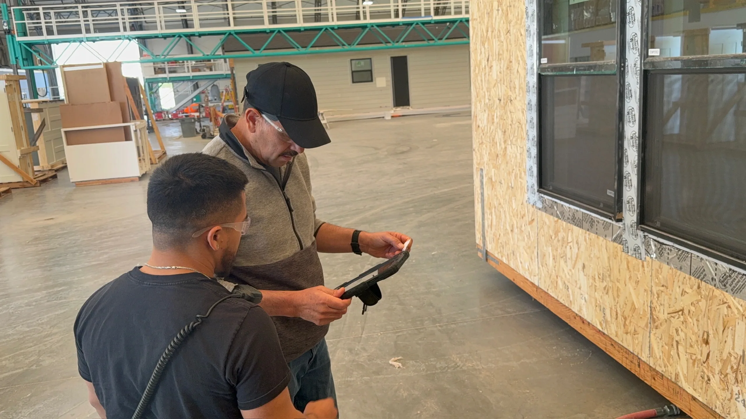 Two people on a modular factory floor checking a build on a tablet
