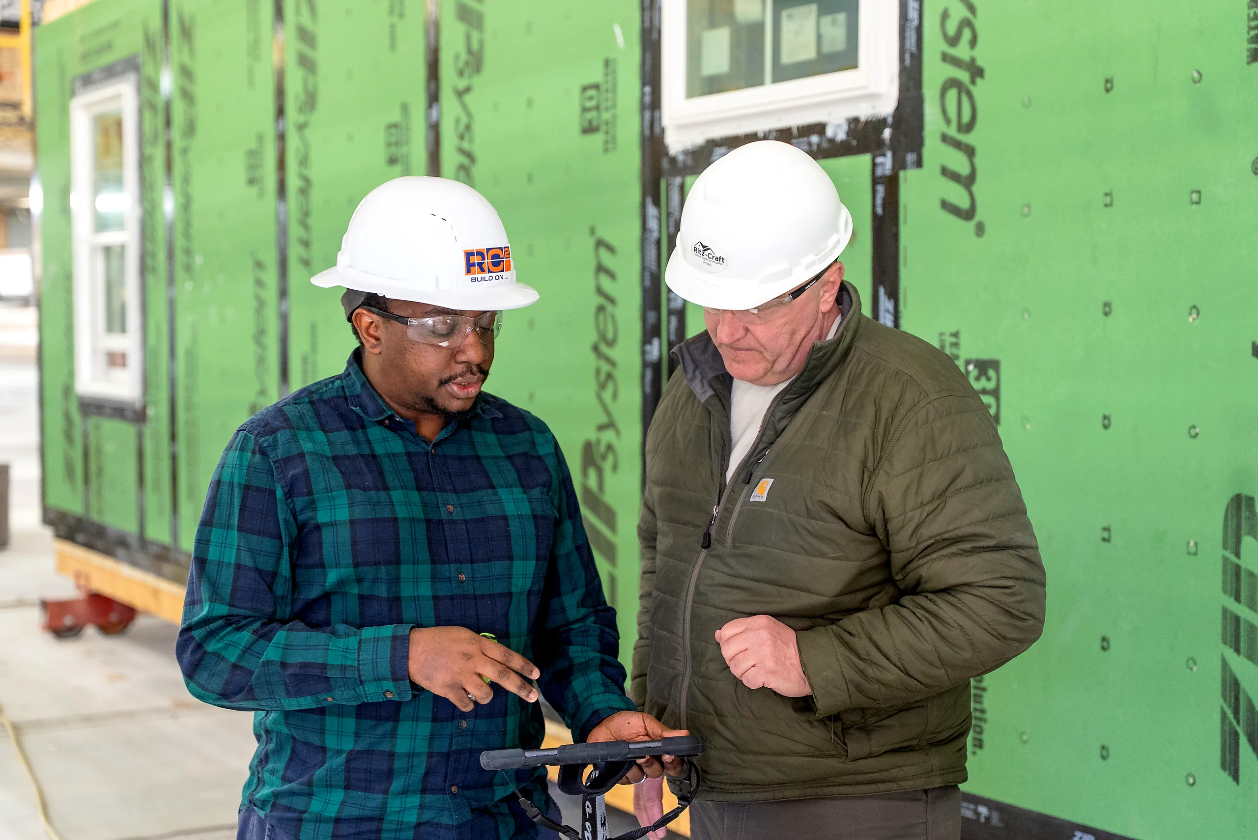 Two operators comparing the build against a tablet